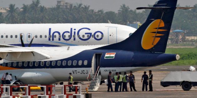 Airport staff stand next to parked passenger jets of IndiGo and Jet Airways.