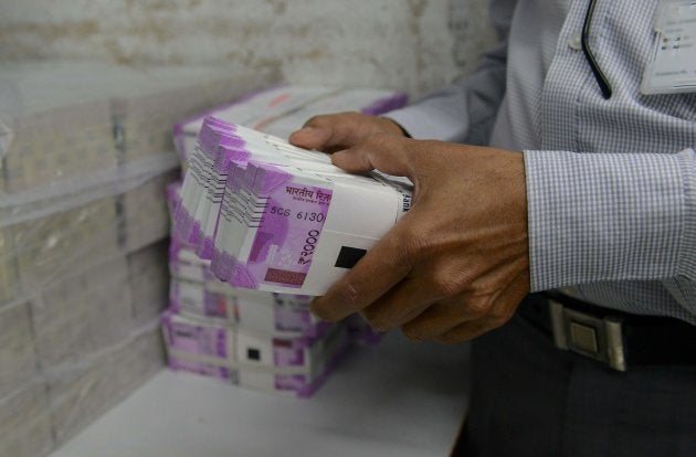 An Indian bank employee checks stacks of new 2000 rupee notes in Ahmedabad on November 11, 2016.