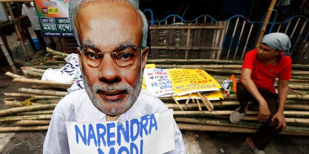 A supporter of Congress party sits next to an effigy of Indian Prime Minister Narendra Modi during a protest against the implementation of the Goods and Services Tax (GST) in Kolkata, July 2, 2017.