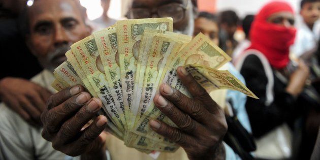 A file photo of a man holds up old versions of the Rs 500 notes as people queue inside a bank to deposit Rs 500 and Rs 1000 notes in Rahimapur village on the outskirts of Allahabad on November 10, 2016.