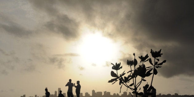 Indians stroll near the seafront as dark clouds gather over city skyline in Mumbai on June 27, 2012. Indian agriculture gets 60 percent of its precipitation from the rains and a bad monsoon can spell financial disaster for the country's 235 million farmers. AFP PHOTO/ Punit PARANJPE (Photo credit should read PUNIT PARANJPE/AFP/GettyImages)