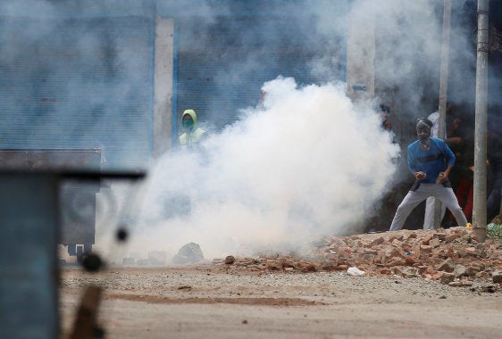 Protesters throw stones amid tear gas smoke fired by Indian police during a protest against the killing of Burhan Wani, a separatist militant leader, in Srinagar, July 10, 2016. REUTERS/Danish Ismail