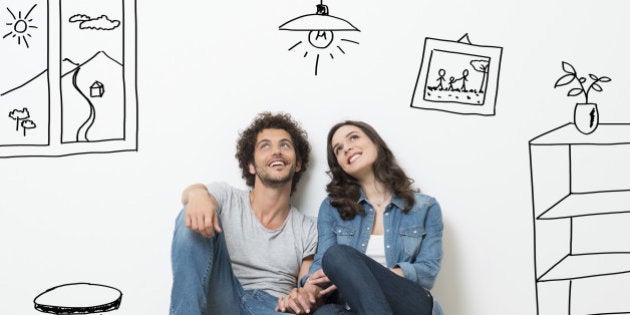 Portrait Of Happy Young Couple Sitting On Floor Looking Up While Dreaming Their New Home And Furnishing