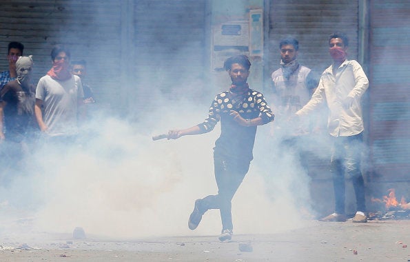 A Kashmiri Muslim protester throws back a teargas shell at Indian paramilitary soldiers in Srinagar, Indian controlled Kashmir, Sunday, July 10, 2016.