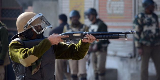 SRINAGAR, JAMMU AND KASHMIR, INDIA - 2016/02/05: A policeman points a pellet gun at protesters during pro-freedom demonstrations in old Srinagar, the summer capital of Indian controlled Kashmir.