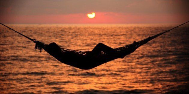 TRIVANDRUM, INDIA - JANUARY 12: A woman relaxes in a hammock at sunset on the beach of Varkala. on January 12, 2010 in Varkala near Trivandrum, Kerala, India. (Photo by EyesWideOpen/Getty Images)