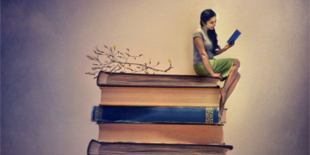 A girl sitting on a pile of book and also reading one. Miniature image.