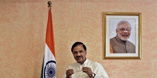 India's Culture Minister Mahesh Sharma, poses next to an Indian national flag and a portrait of India's Prime Minister Narendra Modi before an interview.
