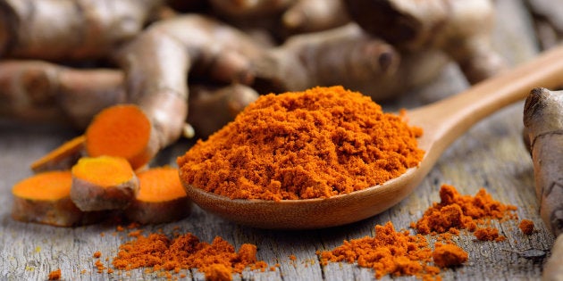 pile of fresh turmeric roots on wooden table