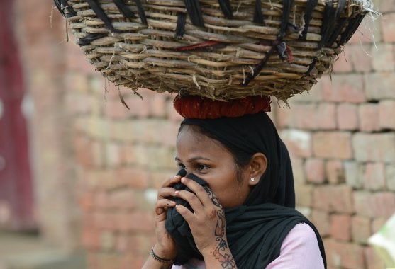 In this picture taken on August 10, 2012, a manual scavenger covers her nose while carrying human waste on her head after cleaning the dry toilets in Nekpur village, Muradnagar in Uttar Pradesh.