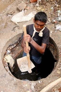 Sanjay Prasad age 33, cleans drains for a living, goes inside a drain with his only tool on July 13, 2012 in New Delhi, India.