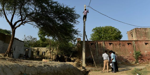 In this photograph taken on 23 April, 2016, an Indian worker climbs up an electricity pole as others look on during the process of electrification in the village of Anandpur in the northern state of Uttar Pradesh.