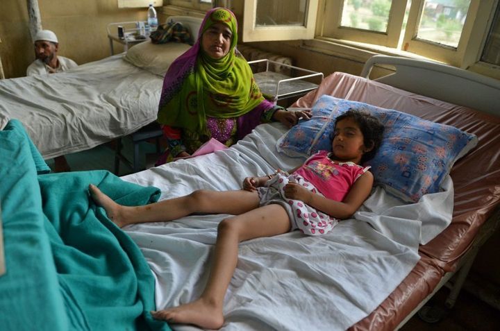 Five year-old Zohra Zahoor, who has pellet wounds in her legs, forehead and abdomen, sleeps on a hospital bed as her aunt Naseema Jan looks on at a hospital in Srinagar on July 13, 2016. (TAUSEEF MUSTAFA/AFP/Getty Images)