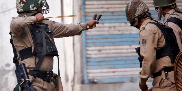 A policeman uses a slingshot to hurl stones towards demonstrators during a protest in Srinagar against the recent killings in Kashmir August 29, 2016.