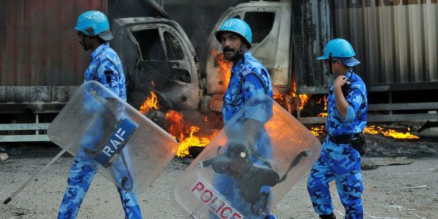 Members of the security forces make their way past burning lorries in Bengaluru, India September 12, 2016.