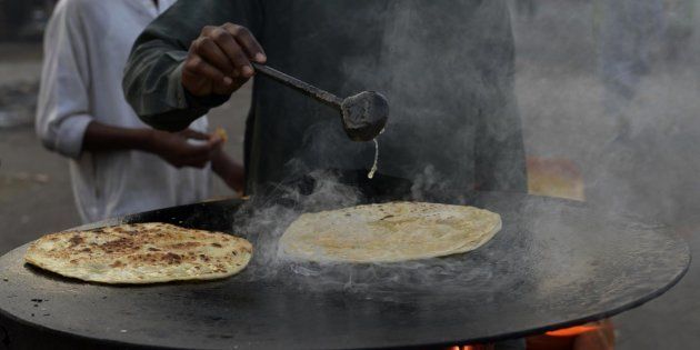 A Pakistani vendor fries aloo paratha (bread stuffed with potato) at a temporary roadside stall in Lahore on October 22, 2014. AFP PHOTO/ Arif ALI (Photo credit should read Arif Ali/AFP/Getty Images)