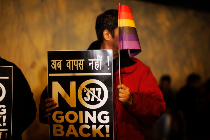 An Indian gay rights activist holds up a placard and a flag during a protest against a recent Supreme Court verdict that upheld section 377 of the IPC