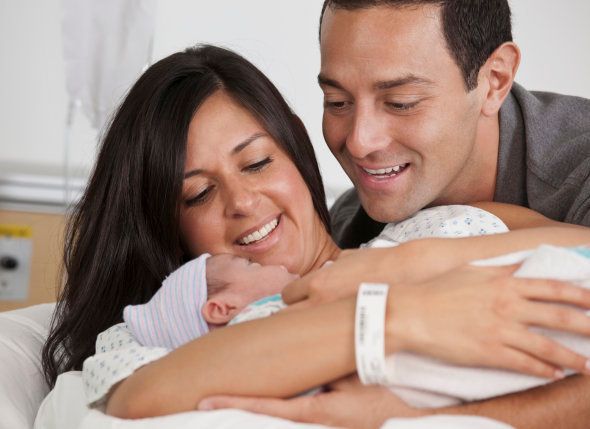 Hispanic parents looking at newborn baby