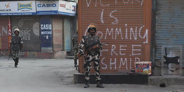 An Indian paramilitary soldier stands alert near a pro freedom graffiti in curfew.