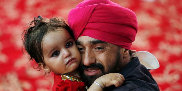 An Afghan Sikh holds his child inside a Gurudwara, during a religious ceremony in Kabul, Afghanistan June 8, 2016.
