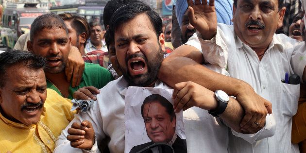A demonstrator hits a poster of Pakistan's Prime Minister Nawaz Sharif during a protest organised by the Congress party.
