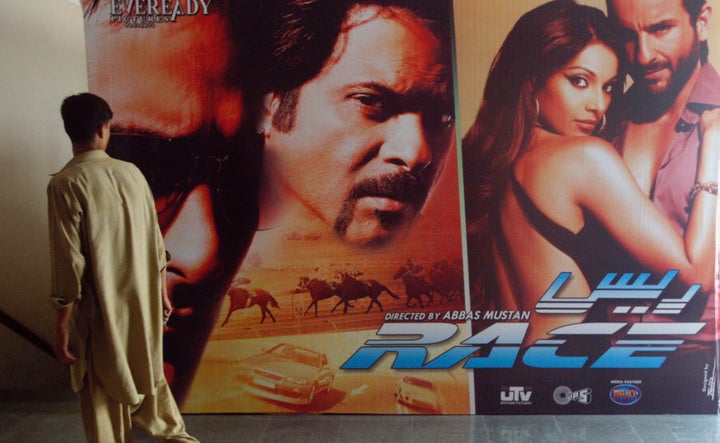 A man walks past an Indian movie poster inside a cinema in Karachi April 21, 2008. Pakistan banned Indian films after going to war with its neighbour in 1965 but over the past few years, as relations between the nuclear-armed rivals have improved, authorities have been allowing a trickle of Indian films to be shown in cinemas. That has delighted movie fans and cinema operators but Pakistani film producers fear a flood of Indian films could mean the end of the local film industry. Picture taken April 21, 2008. To match feature PAKISTAN-BOLLYWOOD/ REUTERS/Athar Hussain/Files (PAKISTAN)