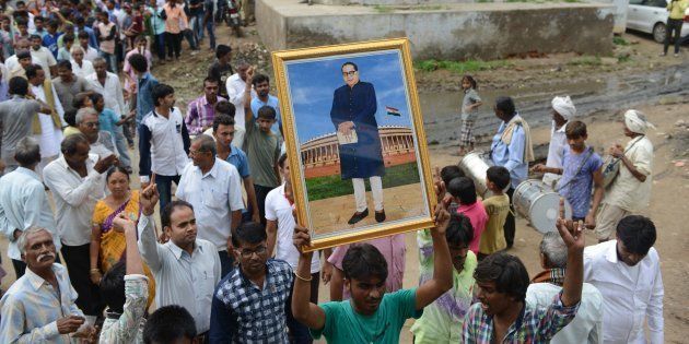 A member of the Dalit community holds up a picture of social reformer Bhimrao Ramji Ambedkar during the Dalit Asmita Yatra rally in Valthera village in Dholka Taluka, near Ahmedabad on August 6, 2016. SAM PANTHAKY/AFP/Getty Images