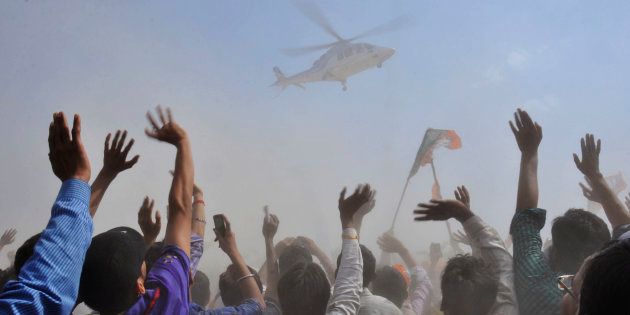 People wave towards a helicopter carrying Narendra Modi in Uttar Pradesh April 21, 2014.