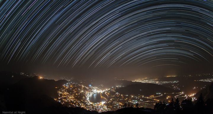 The classic view of the Naini Lake as seen from the vantage point of Naina Peak, with star trails of the south arch seen over the town.