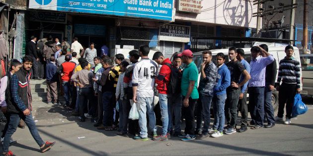People wait in a queue to deposit or exchange discontinued currency notes outside a bank.