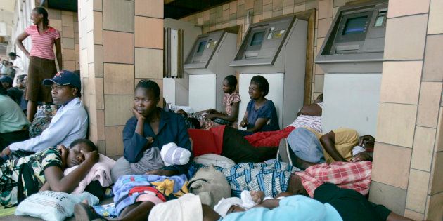 People wait to withdraw money from an ATM at the Central African Banking Savings in central Harare.