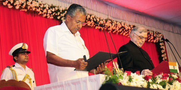 Incoming Chief Minister of Kerala Pinarayi Vijayan (C) stands alongside Governor of Kerala P. Sathasivam (R) as he takes part in a swearing-in ceremony in Thiruvananthapuram on May 25, 2016.