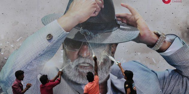 Indian fans spray milk on a poster of Bollywood star Rajinikanth outside a cinema on the first day of release of his new Tamil-language film 'Kabali' in Chennai on July 22, 2016.