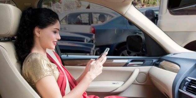 Indian young woman sending a text on mobile phone in car