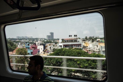 A passenger is silhouetted in front of a window as he rides a train, operated by Bangalore Metro Rail Corp. (BMRCL), in Bengaluru, India, on Sunday, May 3, 2015. Photographer: Sanjit Das/Bloomberg via Getty Images