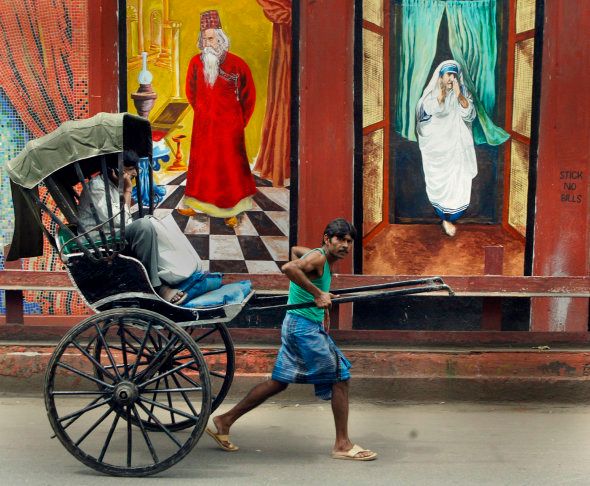 An Indian rickshaw-puller passes murals depicting India's famous Nobel laurete poet Rabindranath Tagore and Mother Teresa.