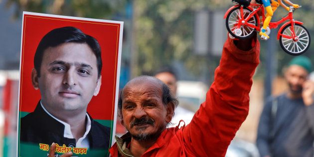 A Samajwadi (SP) party worker holds a toy bicycle representing the party's symbol and a poster of chief minister of northern state of Uttar Pradesh Akhilesh Yadav, following the Election Commission's decision to allot the bicycle symbol in Akhilesh's favour, outside the party's headquarters in Lucknow, India, January 17, 2017.
