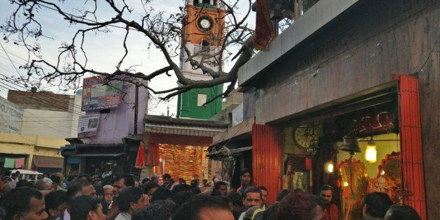 People crowd around a temple in Kasganj, overlooking the clock tower, as it is visited by the BJP's candidate, Devendra Singh Rajput, in the busy Chamunda market of the city.