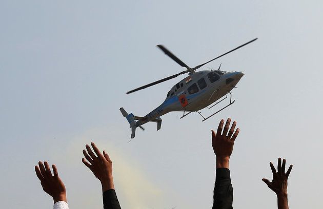 Supporters wave towards a helicopter carrying Keshav Prasad Maurya, the Uttar Pradesh state's president for the ruling Bharatiya Janata Party (BJP), during an election campaign rally in Bah, in the central state of Uttar Pradesh, India, February 2, 2017.