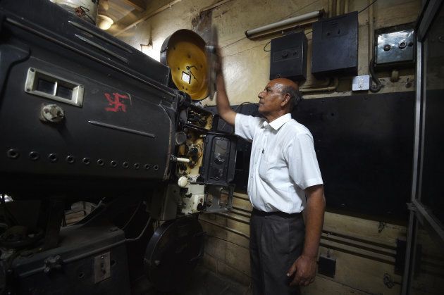 This picture taken on March 27, 2017 shows Indian projectionist Ramesh Kumar, who has worked at the Regal cinema for 23 years, looking at an old projector at the 84-year-old movie hall in the heart of the Indian capital New Delhi.