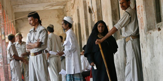 A Muslim woman waits outside a booth to cast her vote as policemen stand guard at a polling station in Varanasi.