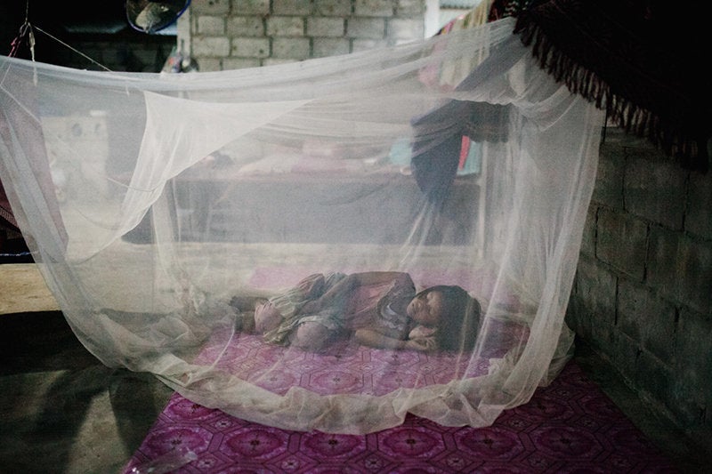 A young girl sleeps under a mosquito net. The bed net is a critical tool for malaria prevention.