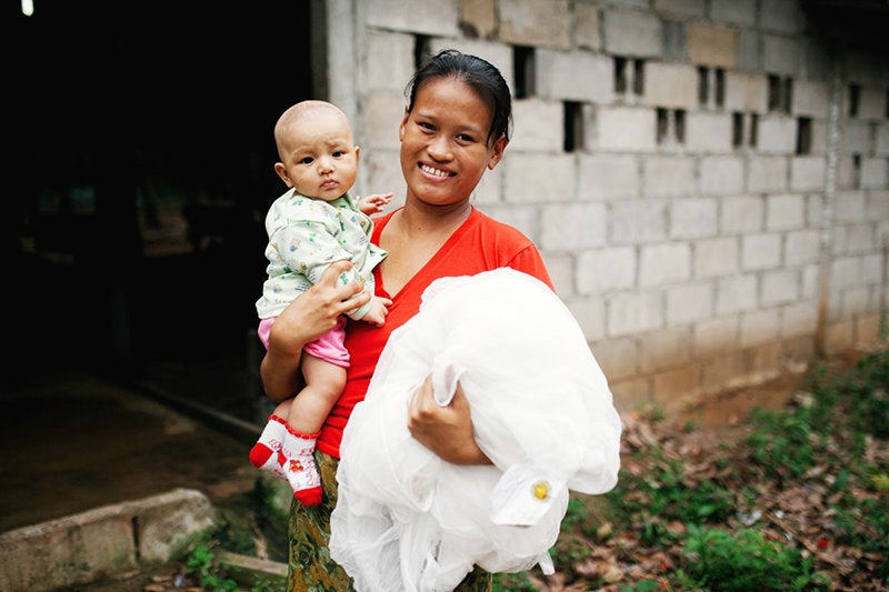 A mother and her young child receive a mosquito net to prevent malaria transmission in Thailand. Pregnant women and children under five are most vulnerable to malaria.
