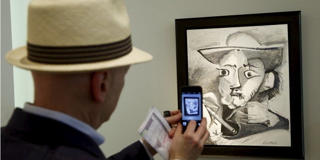 A man takes a picture of the painting