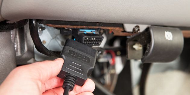 Mechanic Connecting OBD Scanner below SUV Dashboard