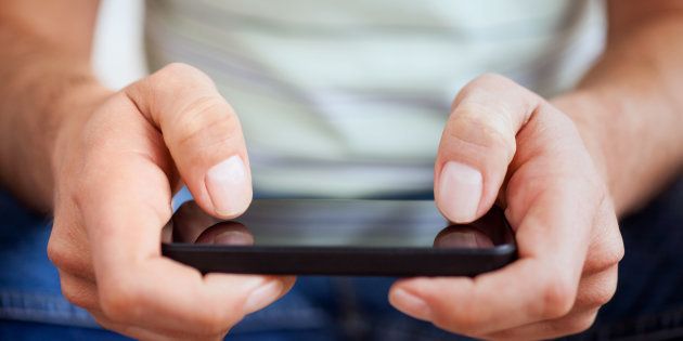 Hands of a casual man using a smartphone.