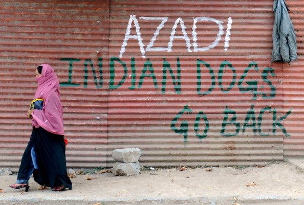 A Kashmiri woman walks past grafitti that reads "Azadi (freedom) Indian dogs go back home" during curfew hours in Srinagar on October 19, 2010. Muslim-majority Kashmir has experienced rolling curfews and strikes since June 11, when a 17-year-old student was killed by a police teargas shell. Since then, more than 110 protesters and bystanders have died in the region. AFP PHOTO/Rouf BHAT (Photo credit should read ROUF BHAT/AFP/Getty Images)