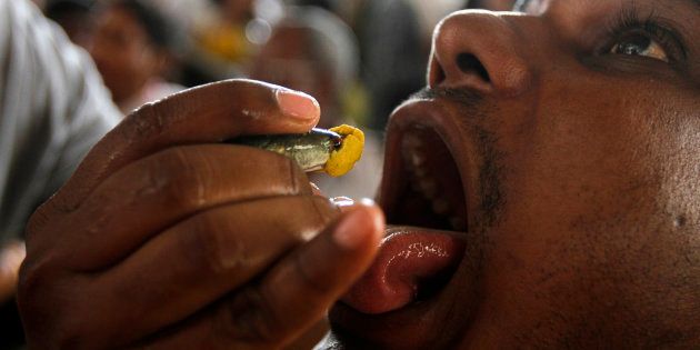 A man prepares to swallow a live fish that has been dipped in homemade medicine as people crowd for their turn in a camp in Hyderabad.