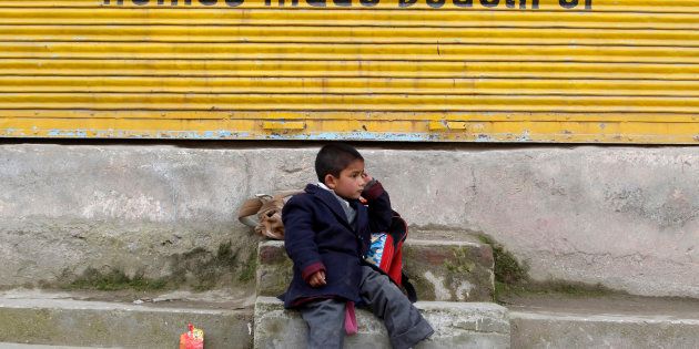 A Kashmiri school boy waits for a bus by a road side in Srinagar March 13, 2012.
