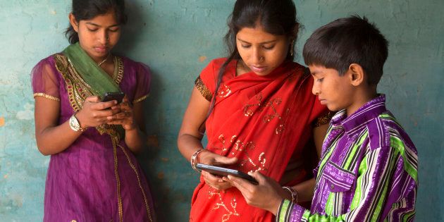 Indian brother and sisters using smartphone and tablet device.